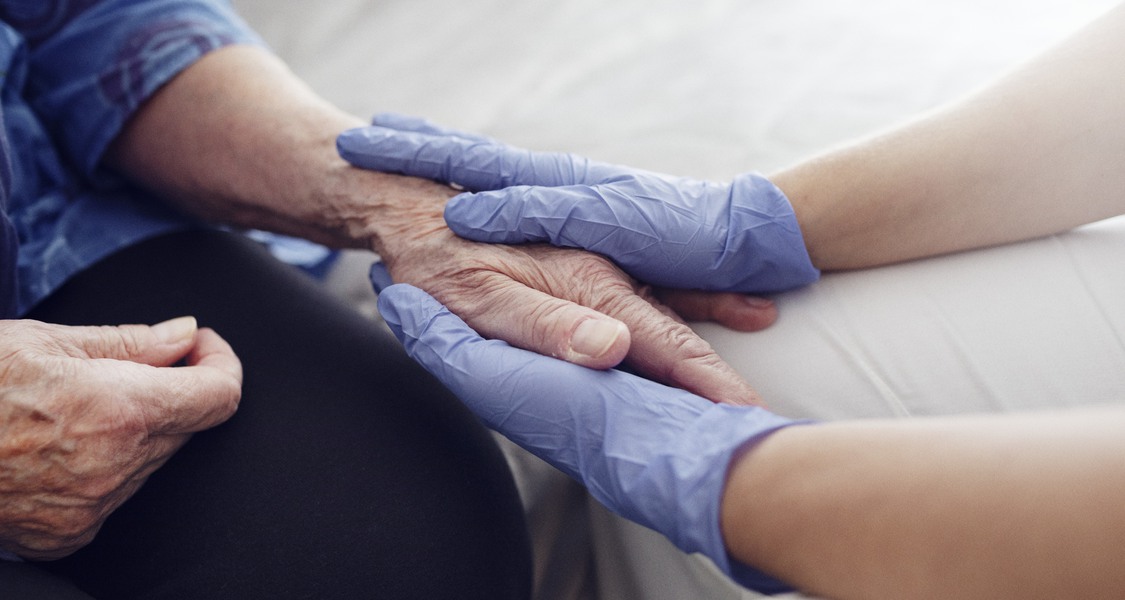 Bild: Äldre kvinna får vård av sjuksköterska hemma.
