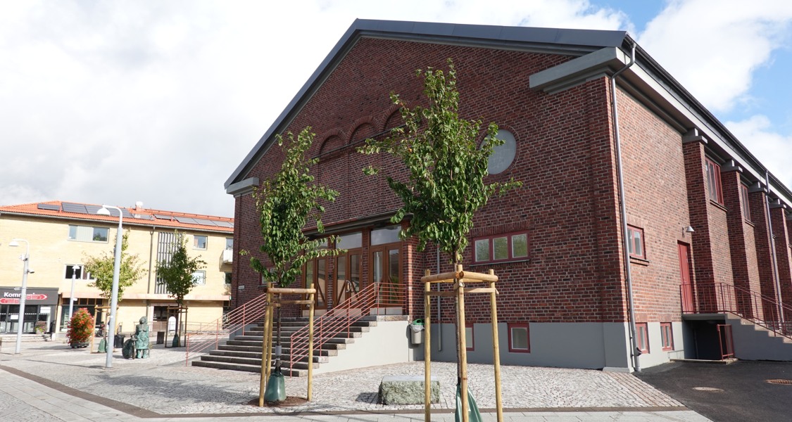 En röd tegelbyggnad med några träd framför sig.