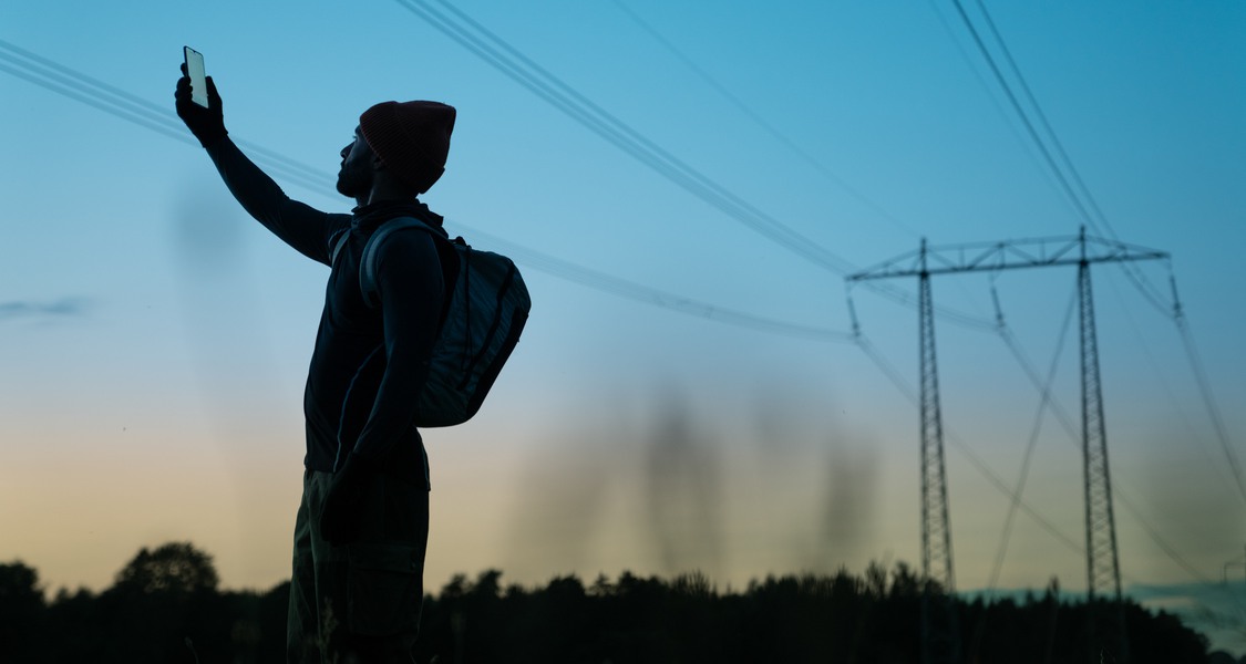 Bild: Man står och håller upp en mobiltelefon mot luften för att få täckning.