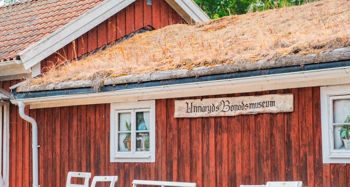 Bild: En faluröd fasad med grästak. Här inne ligger Unnaryds boandsmuseum.
