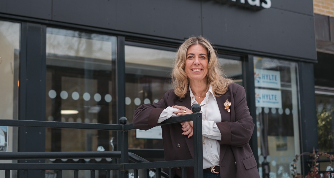 Victoria Bengtsson, kommunchef i Hylte kommun, står lutad mot staketet utanför ingången till kontaktcenter och kommunhuset.