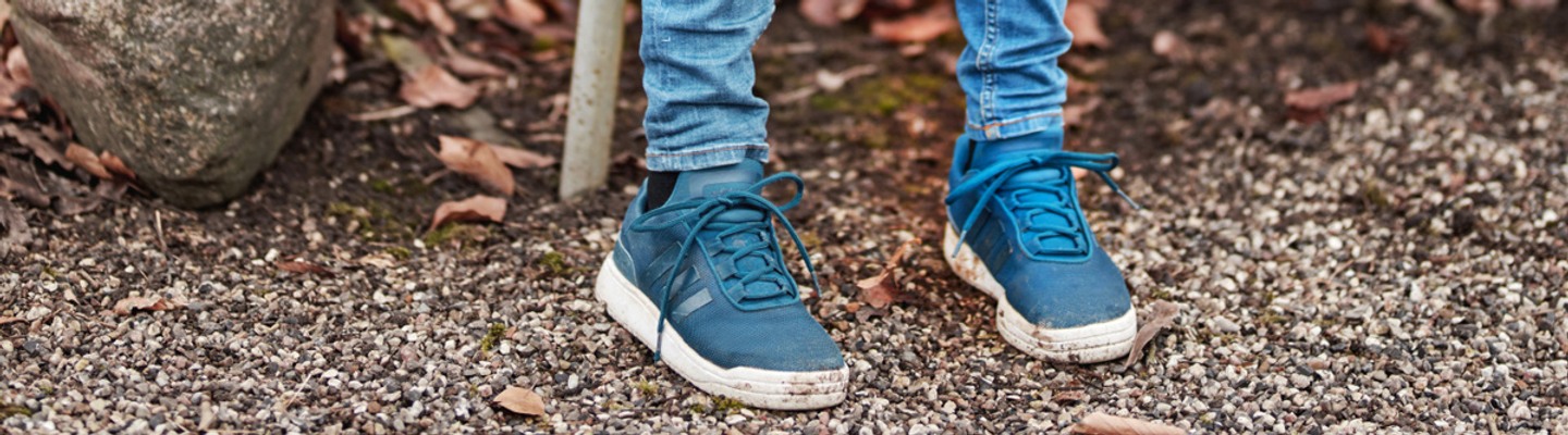En liten pojke som sitter på en bänk i en park.